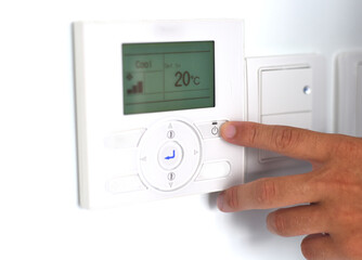 A hand switching on an air conditioner