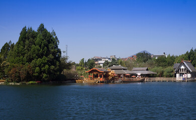 A beautiful Chinese building is situated on the lake's bank with blue water and sky.