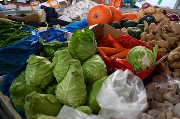 Fototapeta na wymiar Sunday morning at the wet market in Huacao town, metro Shanghai - a wide variety of vegetables on sale at the stalls - leeks, pumpkins, cabage, ginger, scallions, bitter melon, red peppers