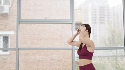 warm-up and stretching. a woman in a burgundy tracksuit exercises in a gym.