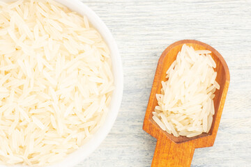 Long Basmati rice in ceramic bowl and scoop on white wooden background. Macro. Flat lay. Diet food concept