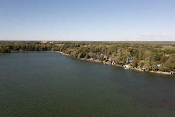 Orillia lake front green trees and lake blue skies drone shot