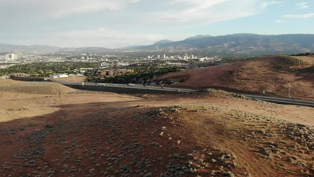 Drone Flight over Hill North of Reno Nevada at Sunset.  Highway 395 North is in the foreground with Downtown Reno in the Distance. - Aerial Drone