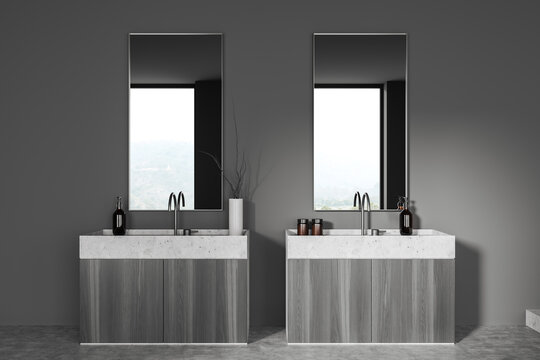 Modern grey bathroom interior with sink and two mirrors, window