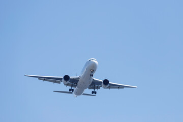青空を背景に羽田空港に着陸態勢に入る飛行機