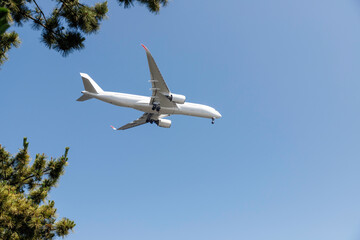 青空を背景に羽田空港に着陸態勢に入る飛行機