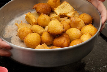 putting sugar and cinnamon in a fried dough known as a 'bolinho de chuva'. a typical and traditional Brazilian recipe