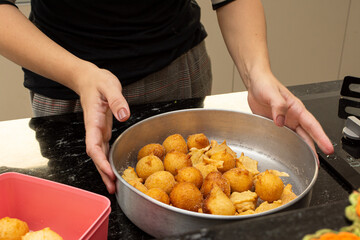 woman putting sugar and cinnamon in a fried dough known as a 'bolinho de chuva'. a typical and...