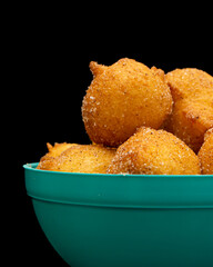 'bolinho de chuva', traditional brazilian recipe, made of fried dough with sugar and cinnamon, in a blue pot and black background. vertical shot