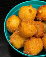 top view of 'bolinho de chuva', traditional brazilian recipe, made of fried dough with sugar and cinnamon, in a blue pot and black background