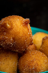 close up shot of 'bolinho de chuva', traditional brazilian recipe, made of fried dough with sugar and cinnamon, in a blue pot and black background. vertical shot