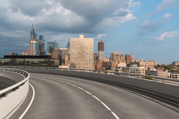 Naklejka premium Empty urban asphalt road exterior with city buildings background. New modern highway concrete construction. Concept way to success. Transportation logistic industry fast delivery. Philadelphia. USA.