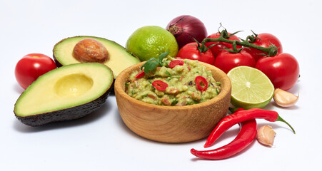 Wooden bowl of guacamole dip sauce and ingredients isolated on white background