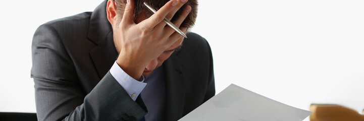 Adult man businessman hold paper sheet in hand and close face with palm