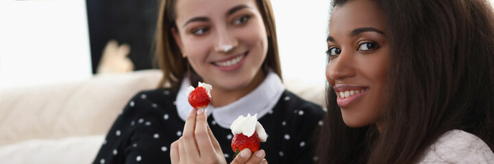 Smiling girls eating tasty fresh strawberry covered with whipped cream