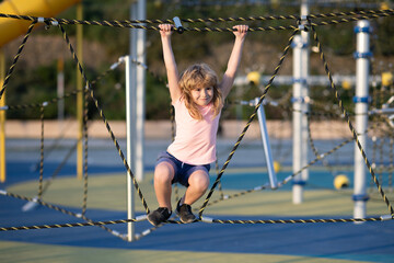 Kids play and climb outdoors on sunny summer day. Child playing at the playground in the garden. Kids having fun on playground.