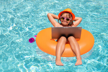 Summer travel and business concept. Kid with laptop in pool water in summer day. Waterproof laptop.