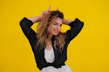 beautiful girl on a yellow background. Pretty brave woman showing wild devilish side making bull...