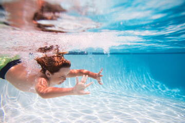 Child in pool in summer day. Kid swimming underwater in pool. Blue sea water. Child boy swimming in sea.