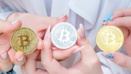 Beautiful female hands with manicure holding 3 souvenir coins of Bitcoin cryptocurrency.