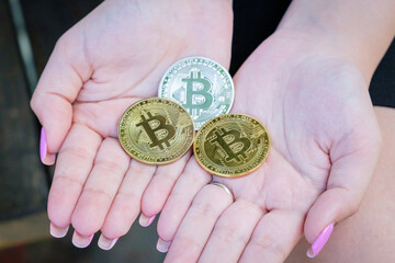 Beautiful woman hands with manicure holding 3 souvenir coins of Bitcoin cryptocurrency. Modern digital crypto gold, e-commerce, internet money of future.