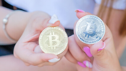Beautiful girls hands with manicure holding 2 souvenir coins of Bitcoin cryptocurrency. Modern digital crypto gold, e-commerce, internet money of future.