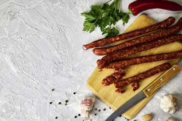 spicy smoked sausages on a cutting board next to red pepper garlic spices and herbs on the table copy space