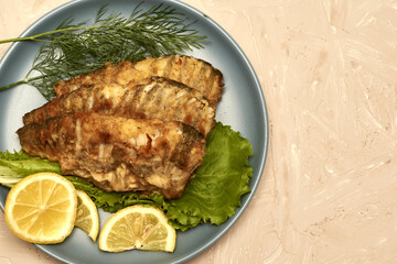 fried fish with lemon and herbs on a plate on the table copy space