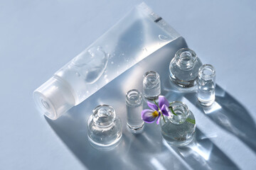 Transparent bottle of cosmetic gel on a blue background with small bottles of water.