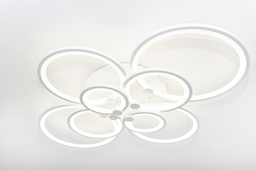 A modern chandelier with eight LED circles of different sizes.