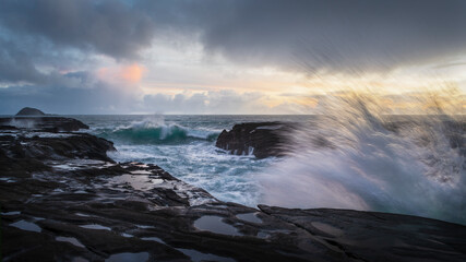Ocean waves crashing on rocks at Muriwai beach, Auckland.