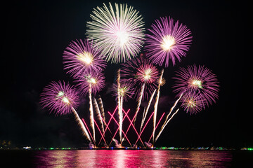 Amazing beautiful colorful fireworks display on celebration night, showing on the sea beach with multi color of reflection on water	