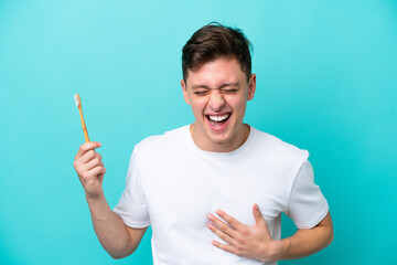 Young Brazilian man brushing teeth isolated on blue background smiling a lot