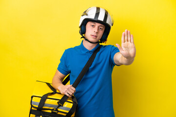 Young Brazilian man with thermal backpack isolated on yellow background making stop gesture