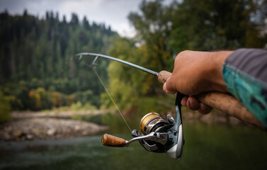 Fishing reel and spinning on stone, blurred background.	