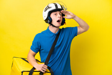 Young Brazilian man with thermal backpack isolated on yellow background doing surprise gesture while looking to the side