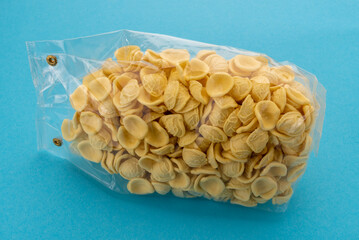 Orecchiette pasta in transparent sealed package for sale on blue background, Italian pasta from...