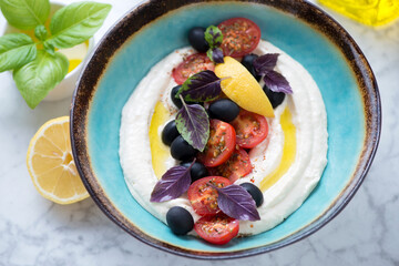 Taramasalata or greek fish roe dip served with cherry tomatoes and olives in a turquoise bowl, middle closeup, horizontal shot