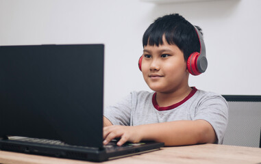 boy wearing headphones playing games on laptop