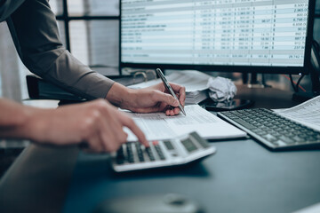 Investors working on desk office and using a pan and pointing to check tracking cost, balance, profit and  currency. Accounting and  Financial concept. - obrazy, fototapety, plakaty