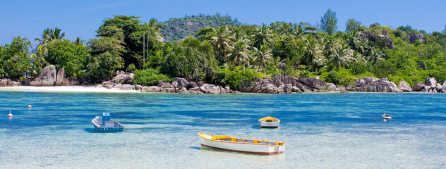 Boat on the shore of a tropical island. Pleasure boat moored on the shore of the resort. Beautiful tropical landscape of the Seychelles. - obrazy, fototapety, plakaty