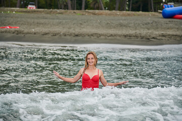 a girl in a red swimsuit bathes on the shore