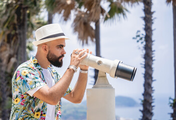 Man watching through binoculars telescope standing on observation point