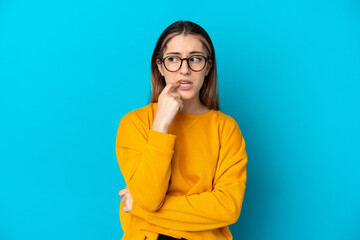 Young caucasian woman isolated on blue background nervous and scared