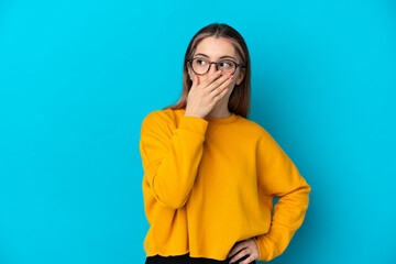 Young caucasian woman isolated on blue background doing surprise gesture while looking to the side