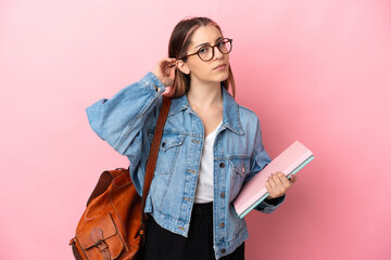 Young caucasian student woman isolated on pink background having doubts