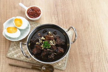 Rawon, Indonesian Traditional beef black soup. Served on a bowl with mung bean sprouts, chilli paste and salted egg

