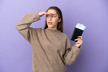 Young caucasian woman isolated on purple background in vacation with passport and plane tickets...
