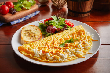 Triple Cheese omelette roll with salad served in a dish isolated on wooden background side view