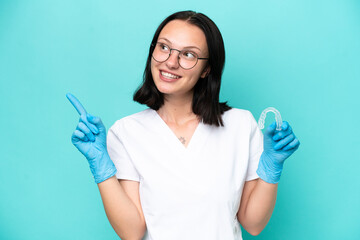 Young caucasian woman holding envisaging isolated on blue background pointing up a great idea